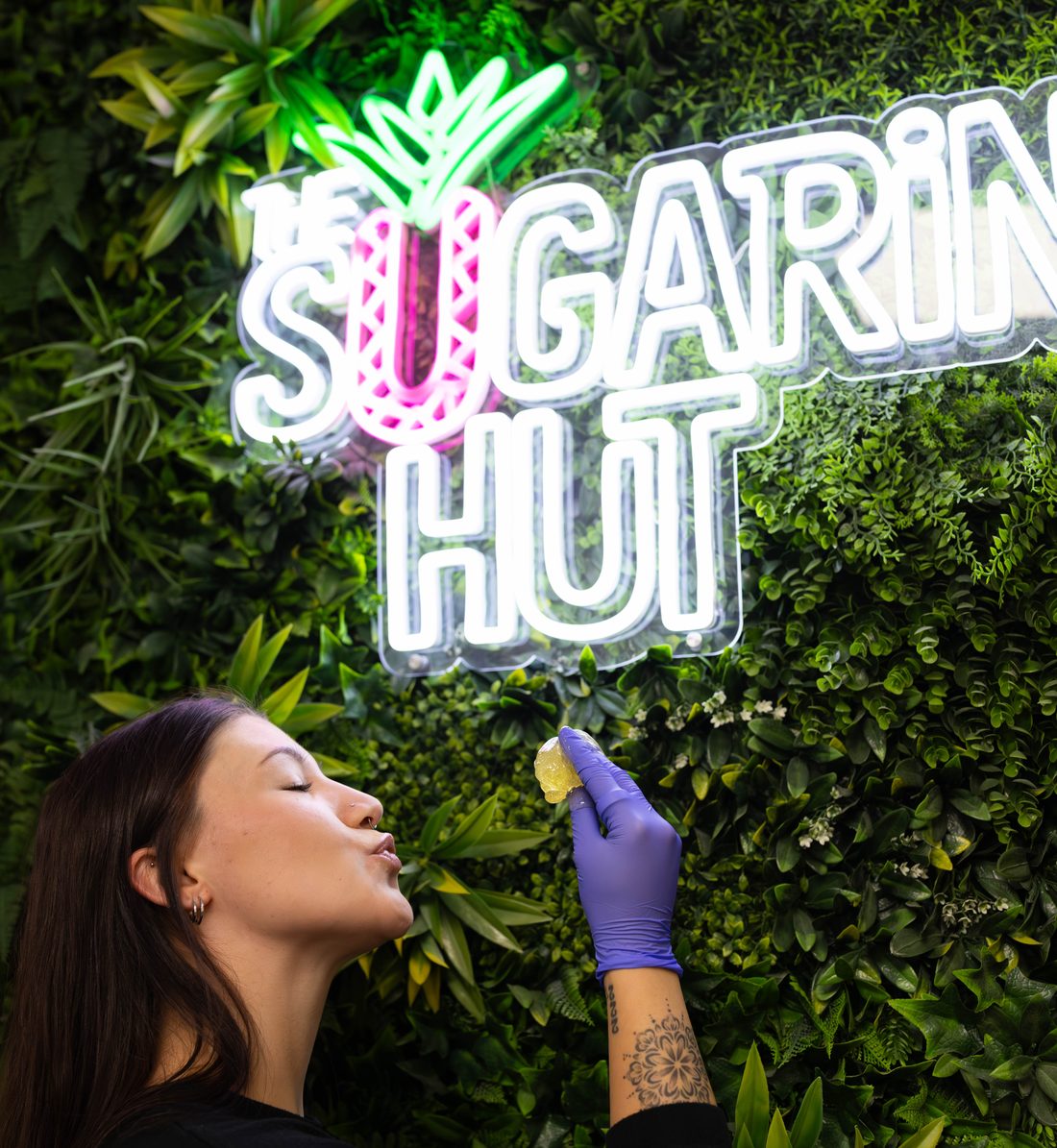 Client kissing a lemon in front of The Sugaring Hut neon sign